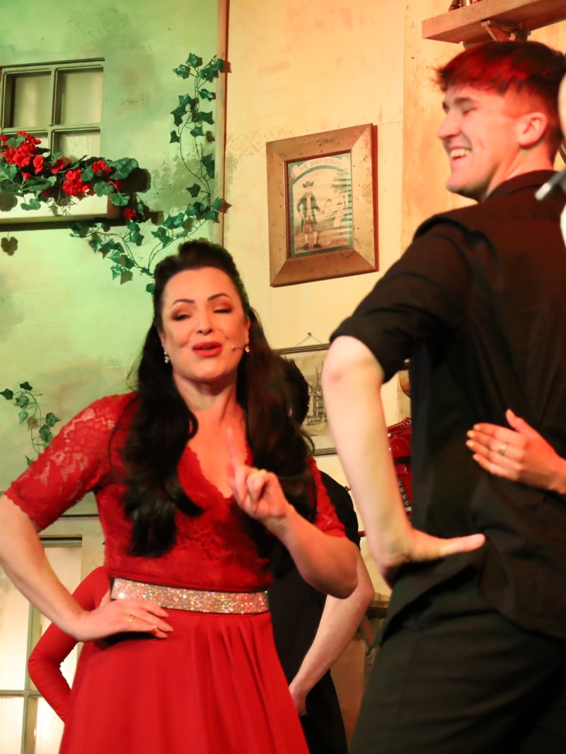 People dancing on stage with bright costumes and cheerful expressions.