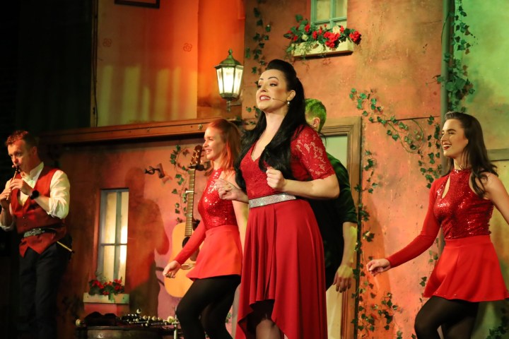 Group of performers in red costumes dancing on stage.